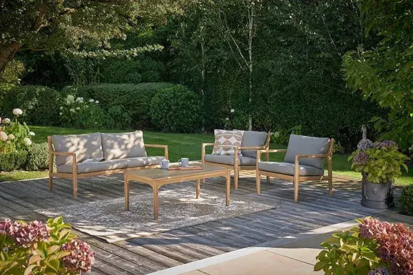 Outdoor seating with timber-framed sofas, grey cushions, and garden backdrop